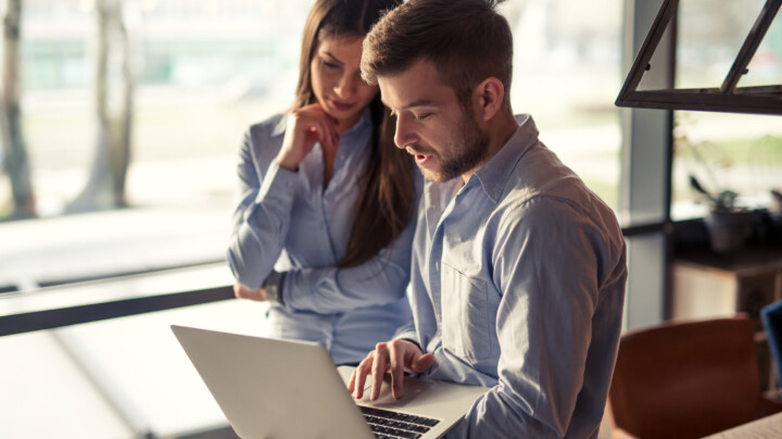 I Need a Health and Safety Plan – Where do I Start? Hero image is of a caucasian man and woman talking whilst the man holds a laptop. They are both in office wear.