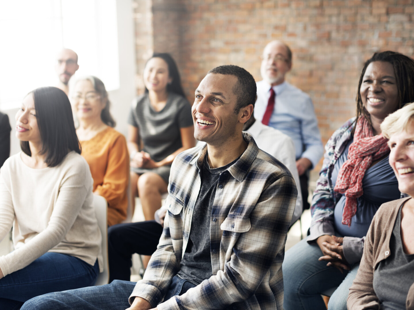 Group of multi-ethnic people sitting in a room all facing the same way, their attention is fixed on What Health and Safety Training in the Workplace Should I Provide?