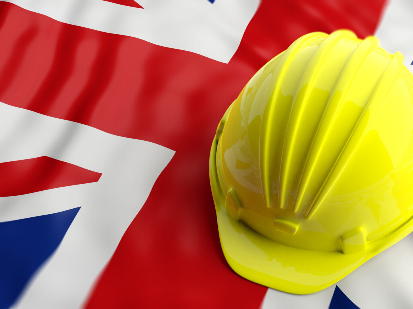 Yellow construction hat over UK flag hero image is PPE is for Life not just covid: The necessary role of personal protective equipment.